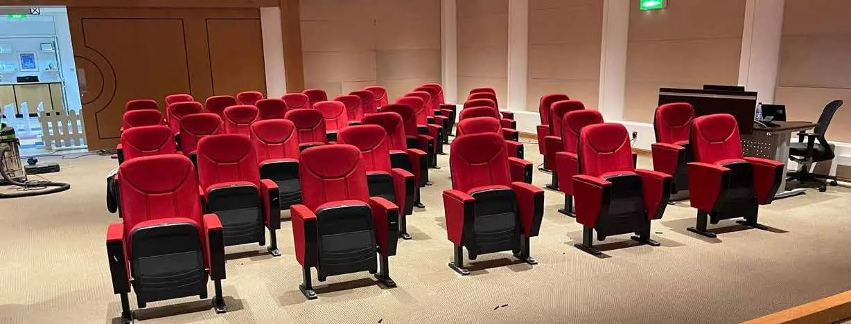 قاعة بصفوف من المقاعد الثابتة المنجّدة